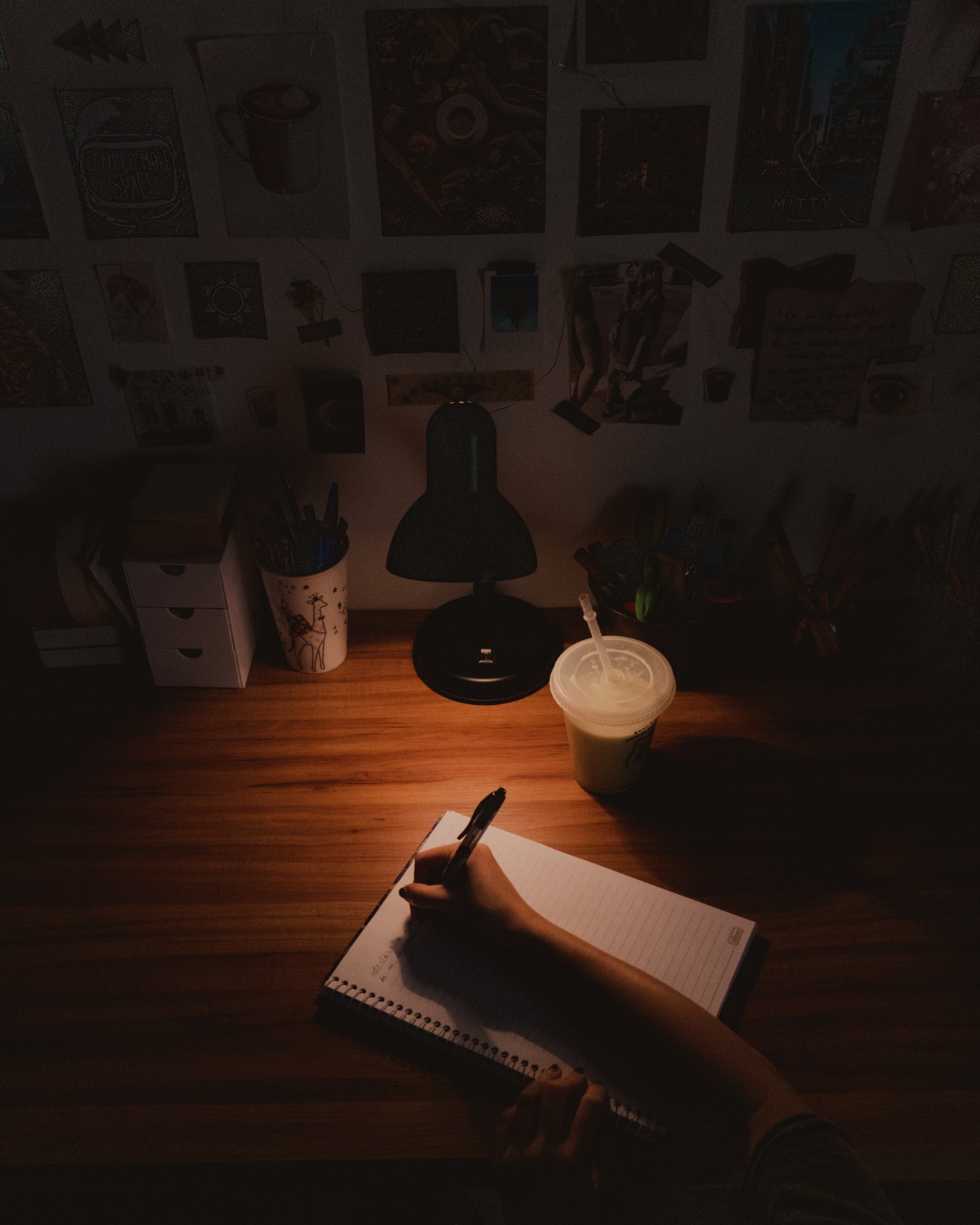 Pessoa escrevendo em um caderno à luz de um abajur, à noite
